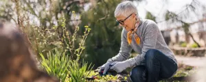 Eine ältere Frau mit kurzen Haaren arbeitet im naturnah gestalteten Garten.