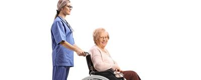 Pflegerin schiebt Frau in Rollstuhl