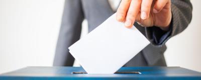 Frau wirft Kuvert in Wahlurne