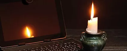 Laptop und Kerze während eines Blackouts